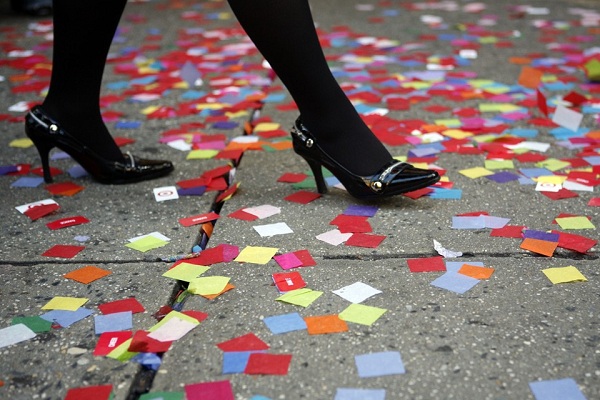 A woman walks on a confetti-strewn sidewalk during a rehearsal for New Year's Eve celebrations at Times Square in New York December 29, 2006. REUTERS/Eric Thayer (UNITED STATES) - RTR1KQU1