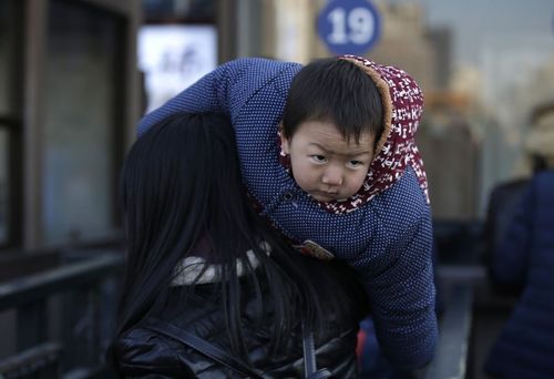 عکس/ مادر و فرزند در حال سوار شدن به قطار در ایستگاه قطار پکن