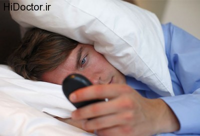 photolibrary_rf_photo_of_man_checking_cellphone_in_bed