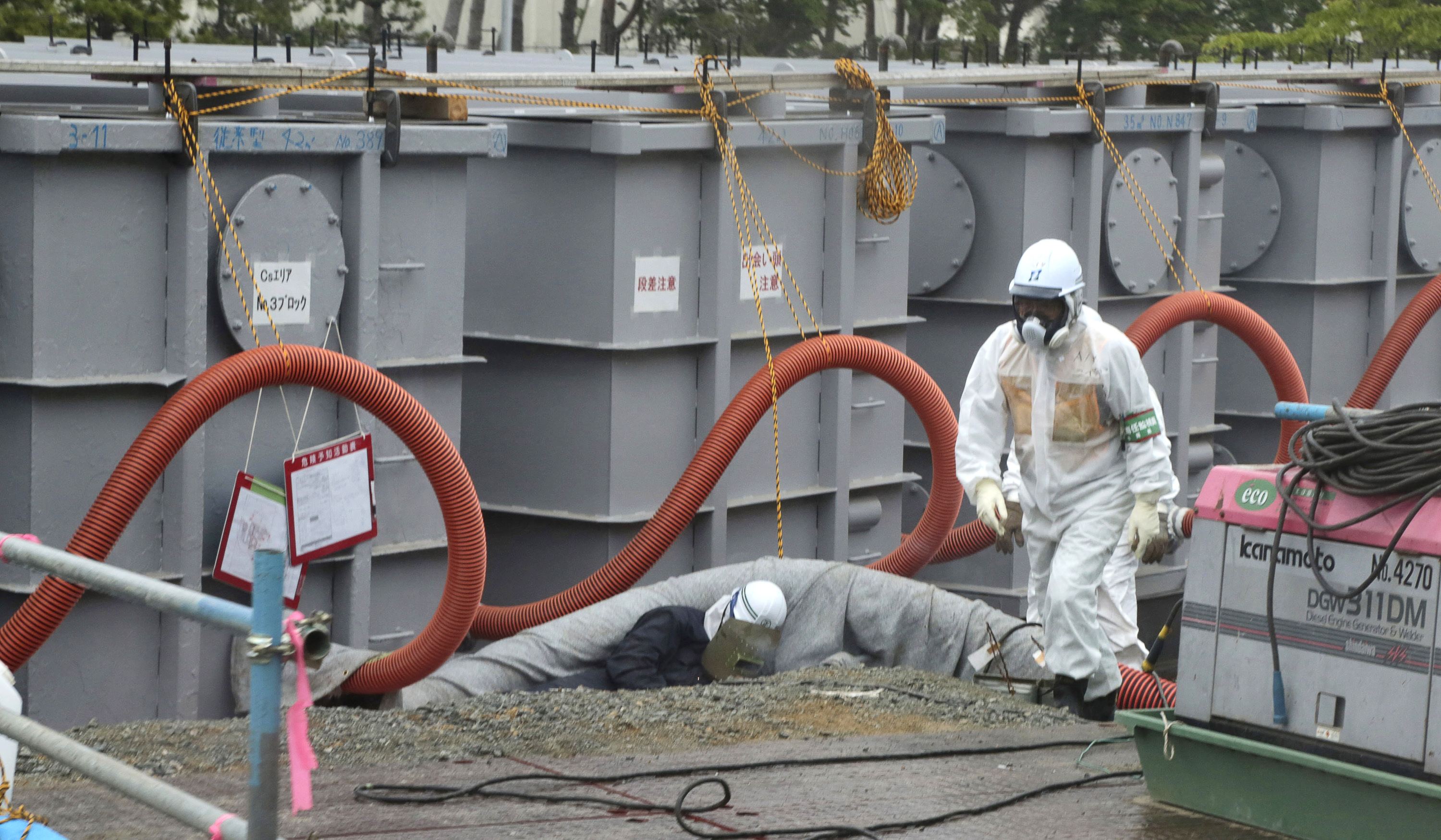 File photo of worker walks in front of water tanks at TEPCO's tsunami-crippled Fukushima Daiichi nuclear power plant in Fukushima prefecture