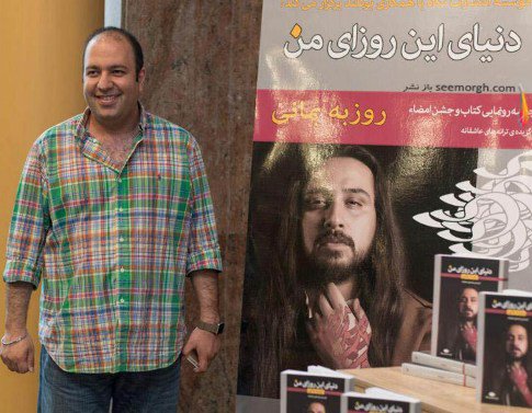 علی اوجی در کنار پوستر کتاب روزبه بمانی