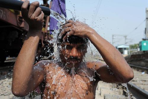 خنک شدن مرد هندی با آب تانکر در ایستگاه قطار 